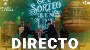 Imagen del sorteo de la Lotería de Navidad retransmitido en directo, con dos grandes bombos dorados sobre un fondo verde, niños con traje escolar y adultos con traje extrayendo bolas frente a una mesa y cámaras — ¿Quién ganó? La sorprendente verdad sobre Lotería Nacional y Navidad