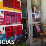 Hombre mayor con mascarilla compra boletos en una ventanilla de lotería frente a grandes pantallas digitales que muestran importes y logotipos de sorteos, ¿Quién ganó más: Cupón Diario o Eurojackpot? Descúbrelo